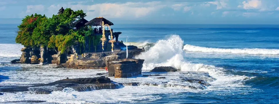 A sea temple and breaking waves at the Tanah Lot temple complex in Bali